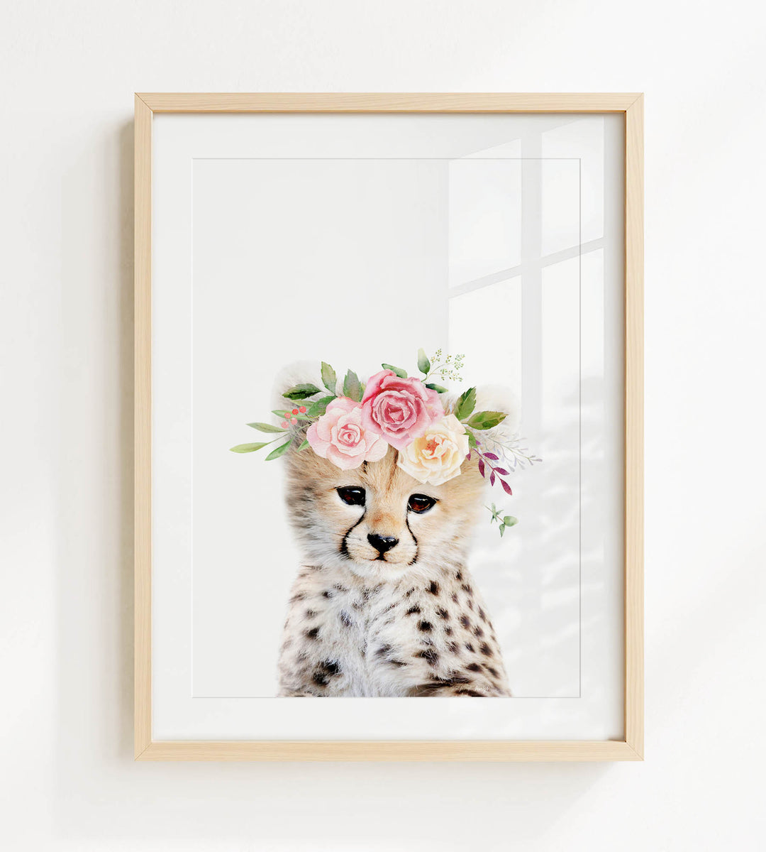 A cheetah wearing a floral crown on its head, with pink and white flowers and greenery.
