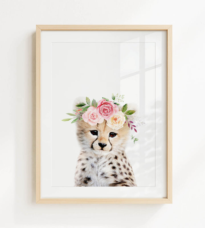 A cheetah wearing a floral crown on its head, with pink and white flowers and greenery.