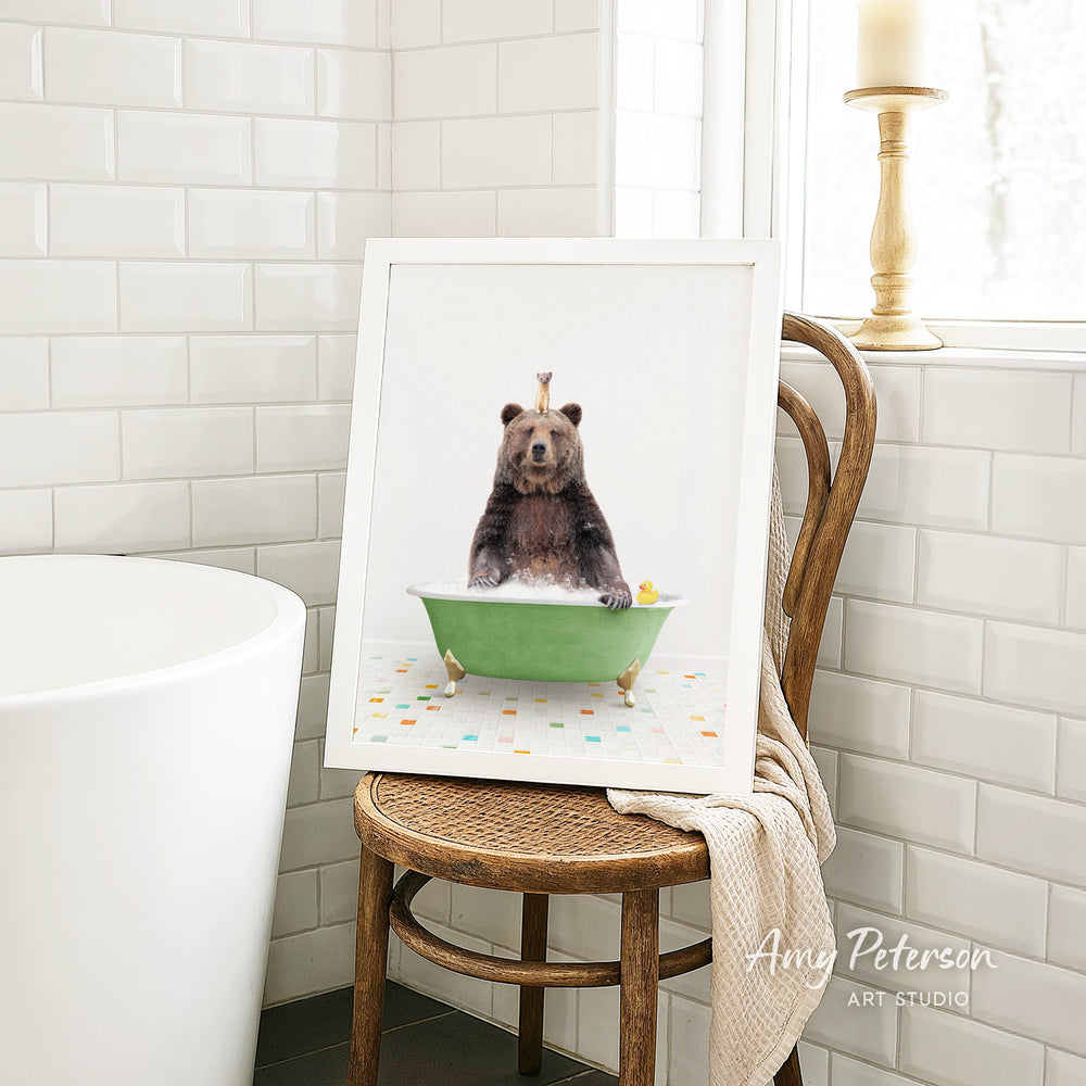 A framed image of a bear sitting in a green bathtub, with a yellow rubber duck floating in the water.