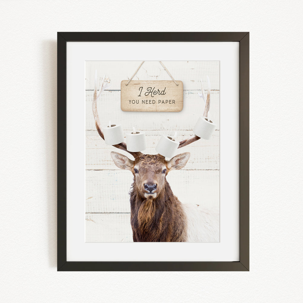 A framed image of a deer with antlers, displaying a sign that says "I herd you need paper".