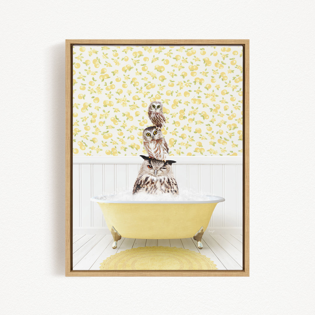 A framed image depicting three owls sitting in a yellow bathtub, with a yellow and white floral pattern on the wall behind them.