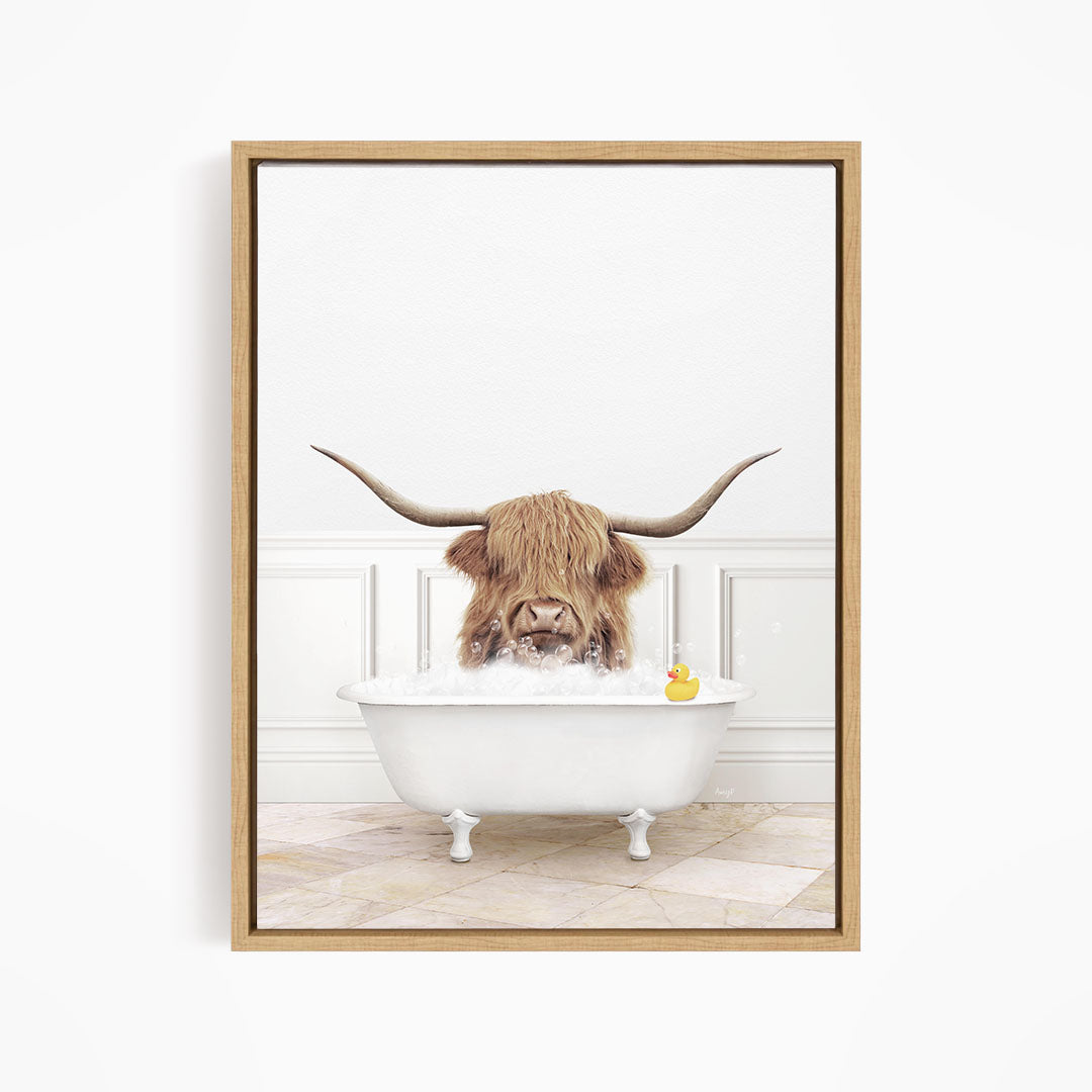 A long-haired cow with large horns is sitting in a white bathtub, surrounded by a yellow rubber duck.