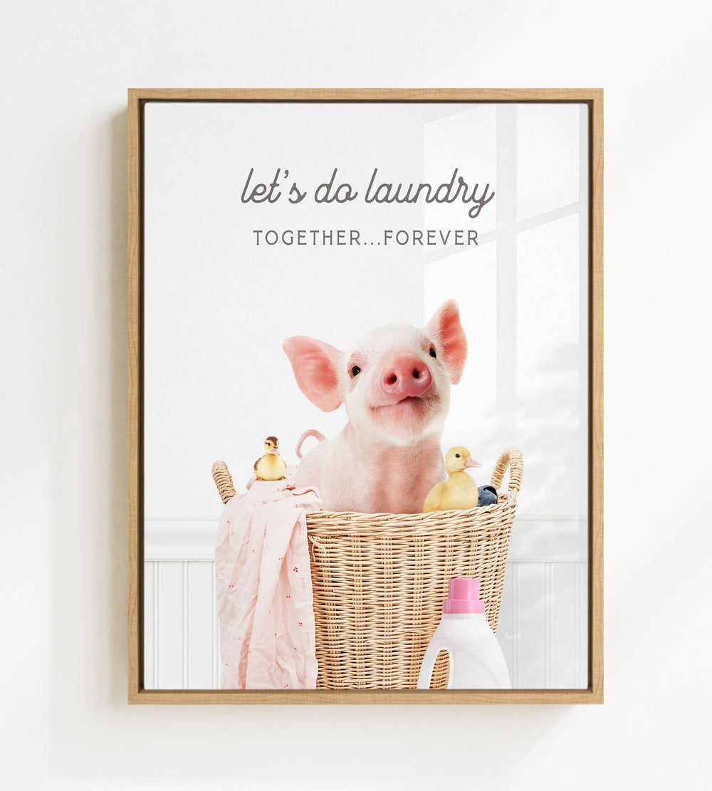 A framed image of a pig sitting in a wicker basket filled with various objects, including a bottle of detergent and a yellow duck.