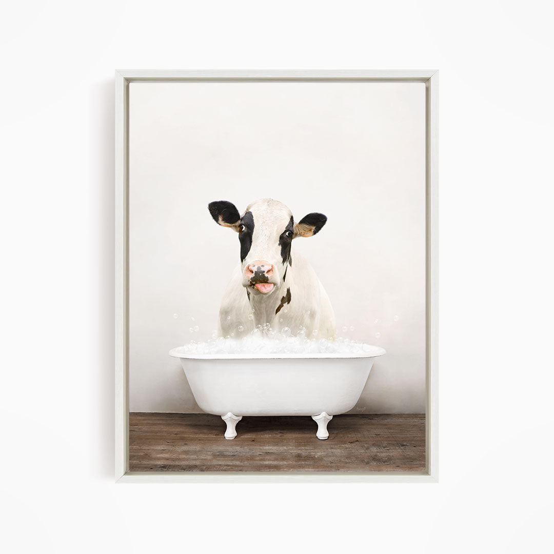 A black and white cow is sitting in a white bathtub filled with water, creating a whimsical and humorous scene.