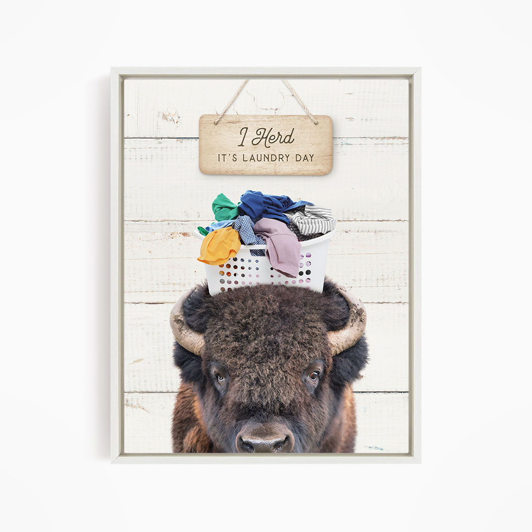 A buffalo with a basket of laundry on its head, accompanied by a wooden sign that says "It's laundry day".