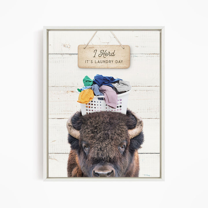 A buffalo with a basket of laundry on its head, accompanied by a wooden sign that says "It's laundry day".
