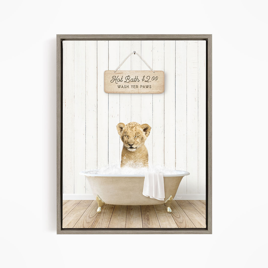 A young lion cub sitting in a bathtub, with a sign above the tub that reads "Hot Bath $2.00 WASH YOUR Paws".