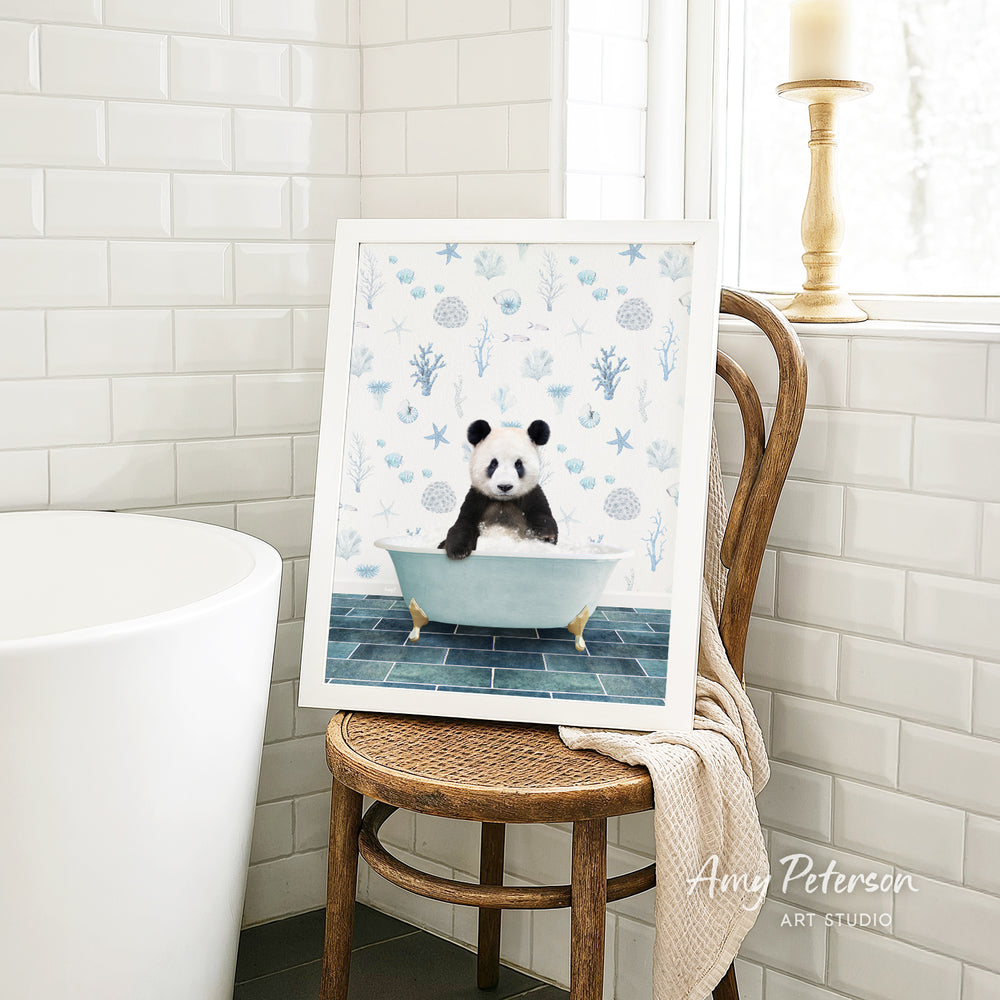 A framed image of a panda sitting in a bathtub is displayed on a wooden chair in a bathroom setting.