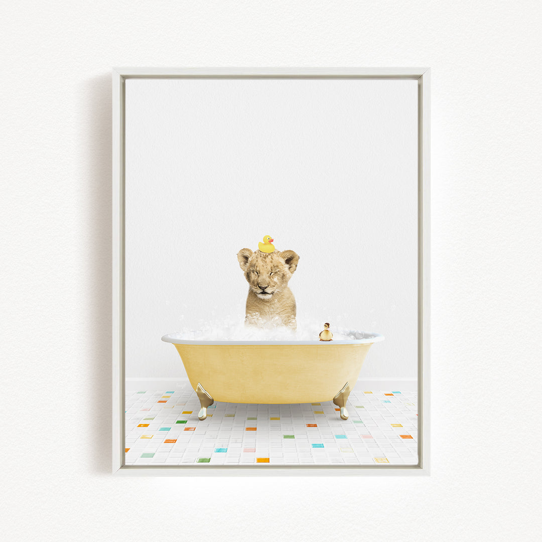 A young lion cub is sitting in a yellow bathtub filled with bubbles, with a yellow rubber duck perched on its head.