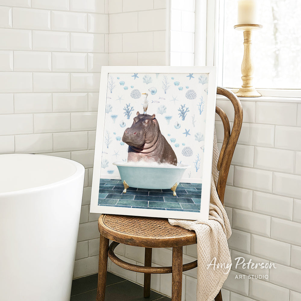 A framed image of a hippopotamus sitting in a bathtub is displayed on a wooden chair in a bathroom setting.