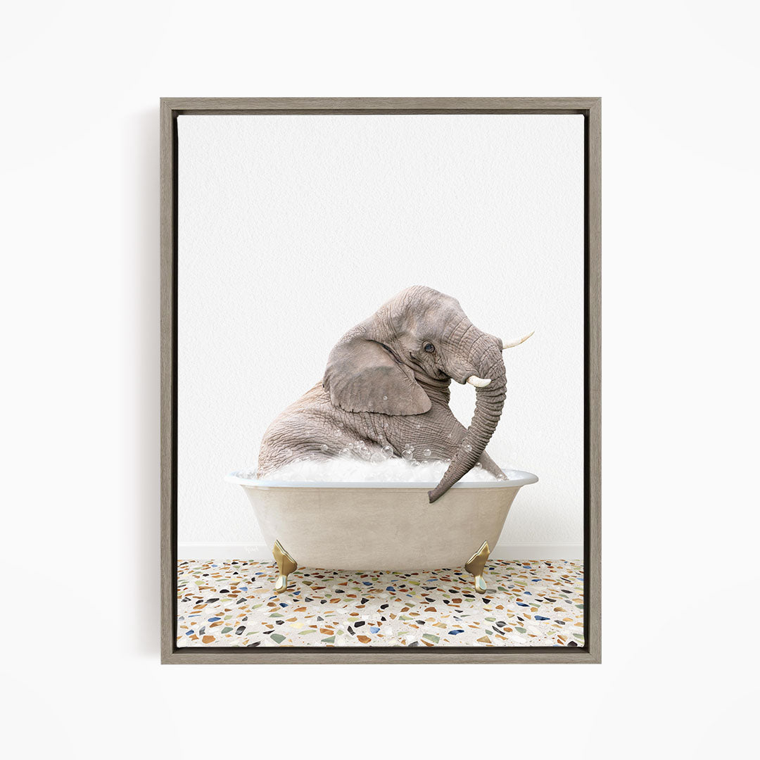 A gray elephant is sitting in a white bathtub filled with water, with its trunk raised and appearing to be enjoying the bath.
