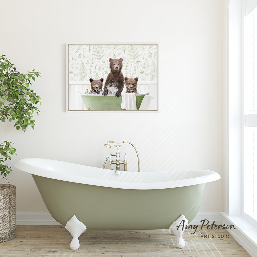 A framed image of three bears sitting in a bathtub is displayed on the wall above a green clawfoot bathtub in a bathroom.