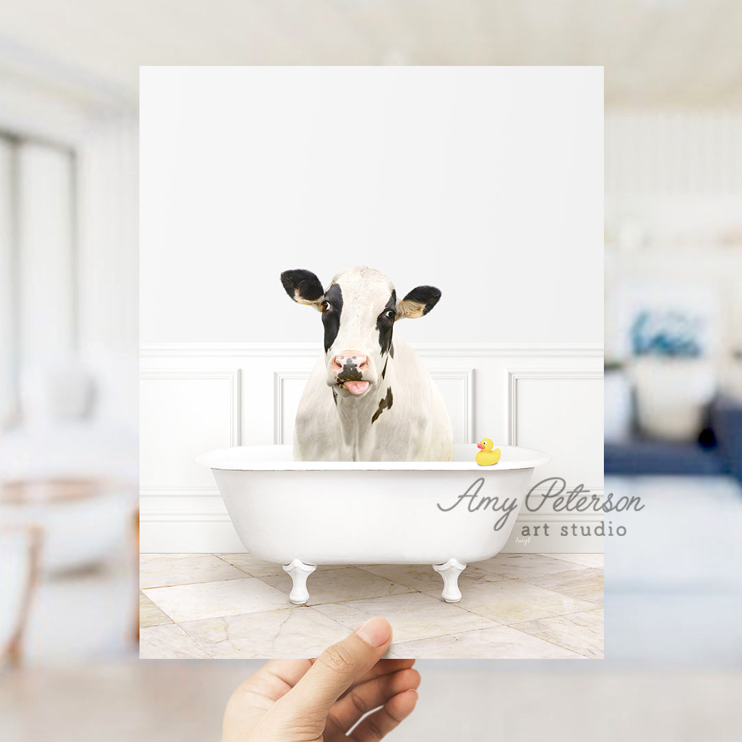 a person holding up a picture of a cow in a bathtub