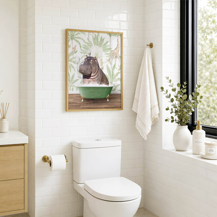 A bathroom with a white toilet, a framed picture of a hippopotamus in a bathtub, and a window with greenery outside.