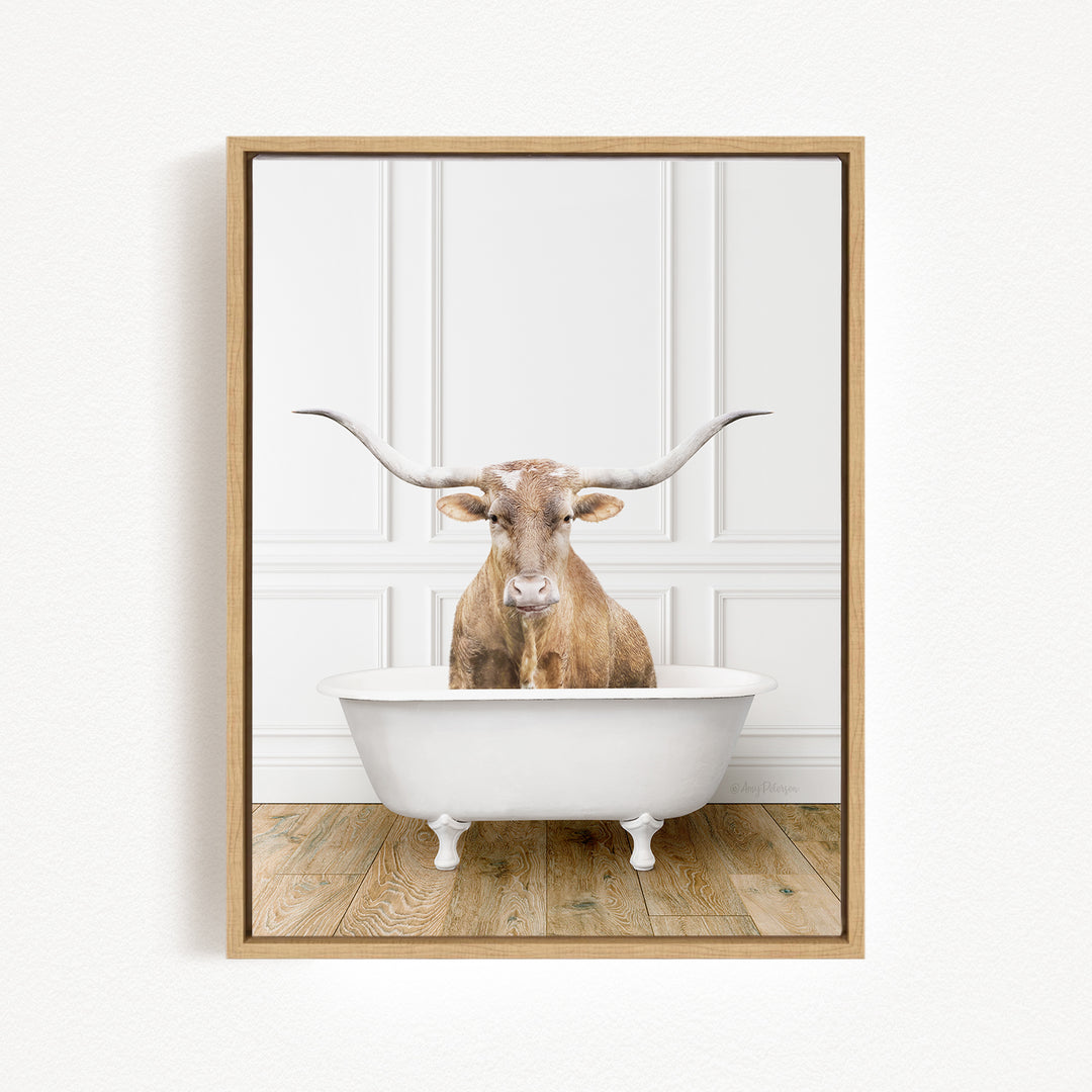 A brown cow with large horns is sitting in a white bathtub, looking directly at the camera.