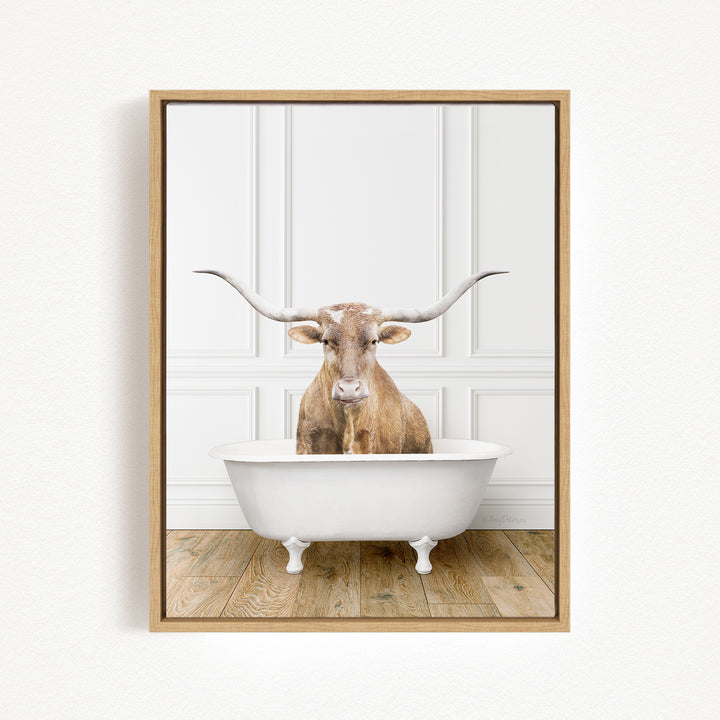A brown cow with large horns is sitting in a white bathtub, looking directly at the camera.