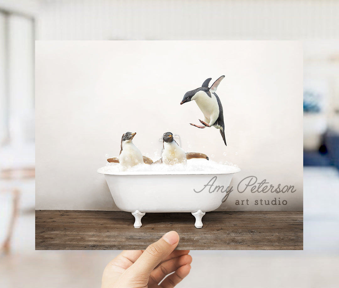 a hand holding up a card with penguins in a bathtub