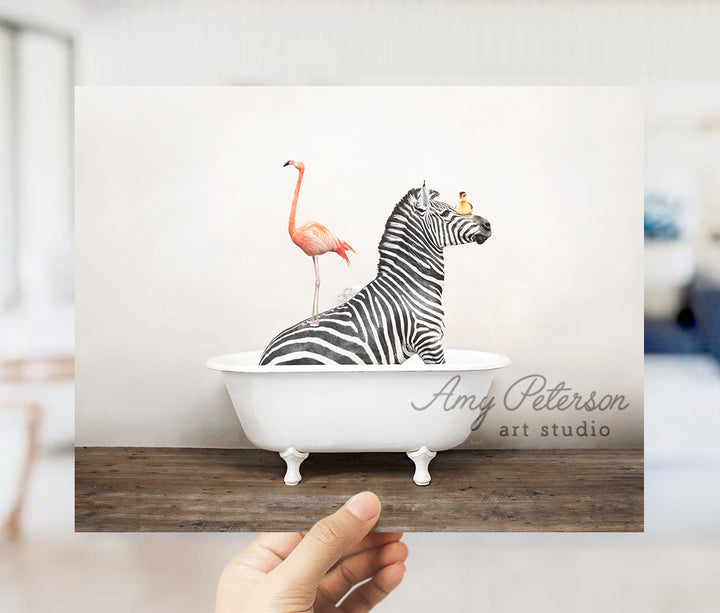 a hand holding a card with a zebra and a flamingo in a bathtub