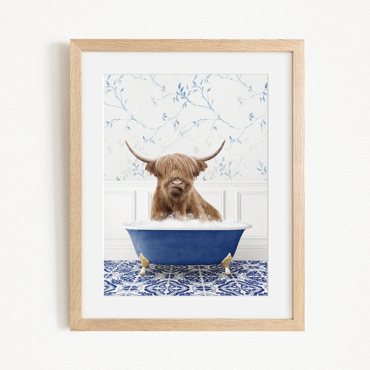 A brown cow with long horns is sitting in a blue bathtub, surrounded by a blue and white patterned rug and a white wall with blue floral wallpaper.