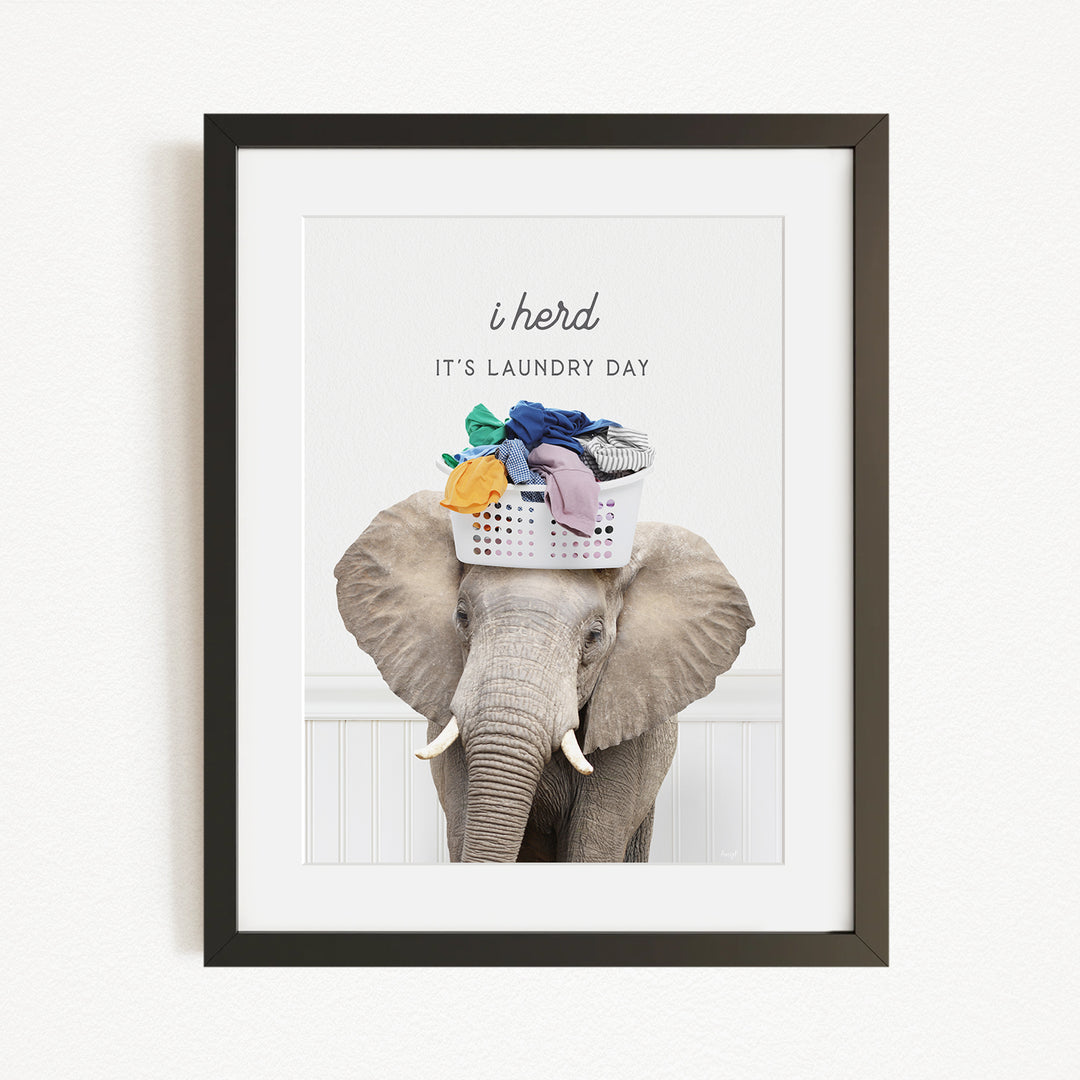 A framed image of an elephant carrying a laundry basket on its head, with the text "It's laundry day" written above it.