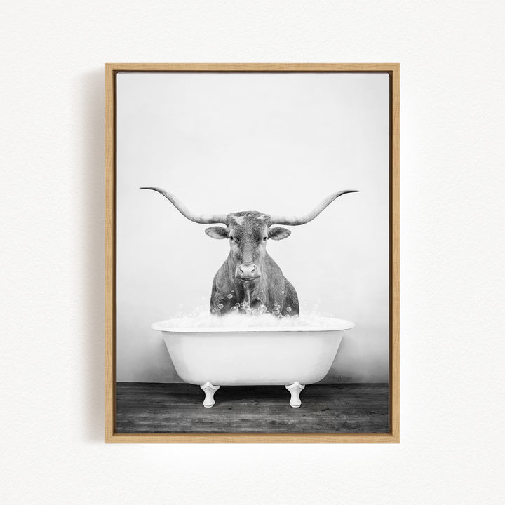 A black and white photograph of a horned animal, possibly a bull or steer, sitting in a white bathtub filled with water.