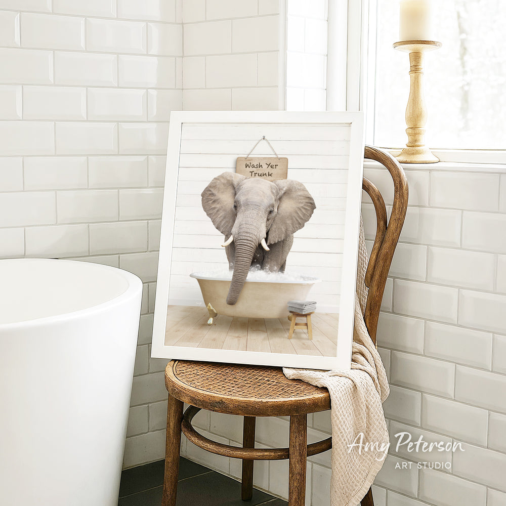 A framed image of an elephant sitting in a bathtub, with a sign above it that says "Whale Your Trunk".