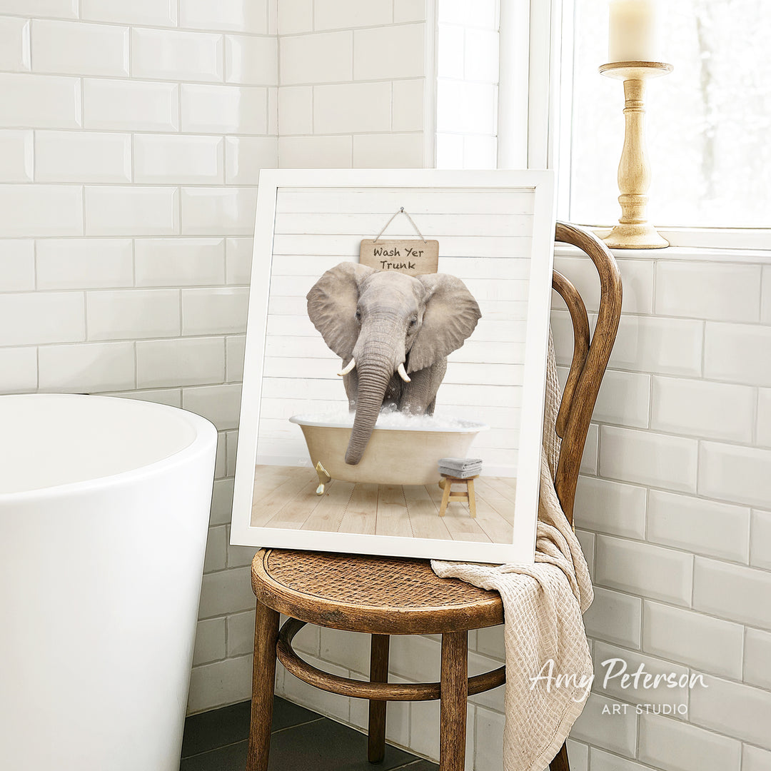 A framed image of an elephant sitting in a bathtub, with a sign above it that says "Whale Your Trunk".