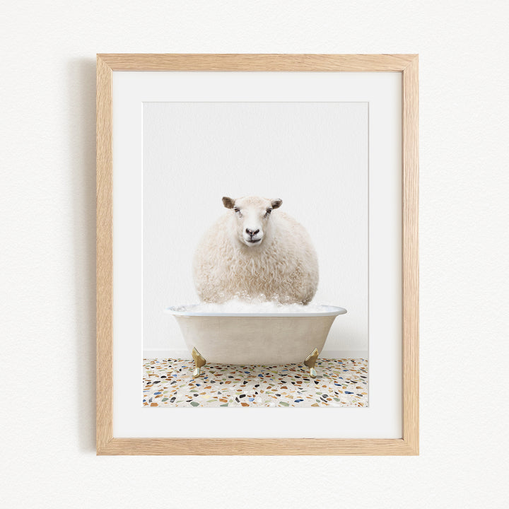 A fluffy white sheep sits in a white bathtub filled with bubbles, creating a whimsical and playful scene.