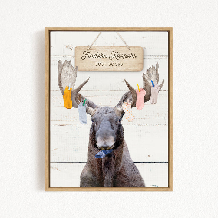 A framed image of a moose with a sign that says "Finders Keepers Lost Socks" hanging above it.