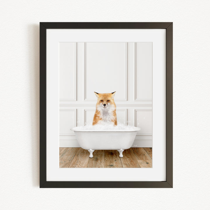 A red fox is sitting in a white bathtub filled with bubbles, looking directly at the camera.