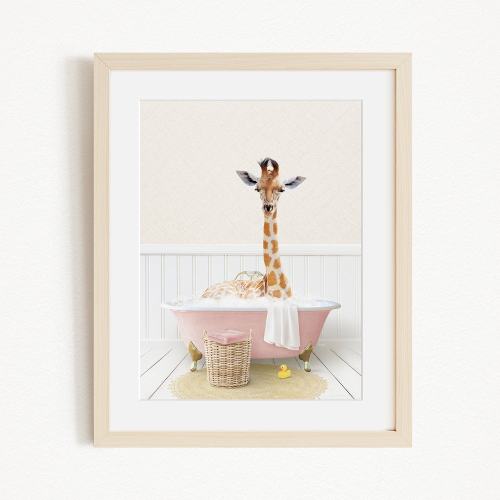 A giraffe is sitting in a pink bathtub filled with bubbles, surrounded by a yellow rubber duck and a basket.