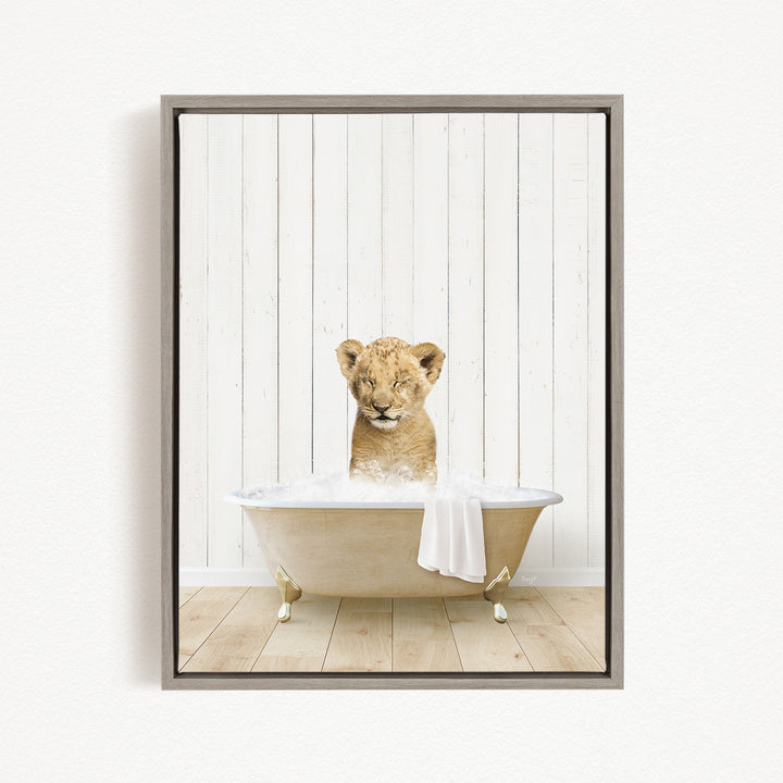 A young lion cub sitting in a bathtub filled with water, with a towel draped over its body.