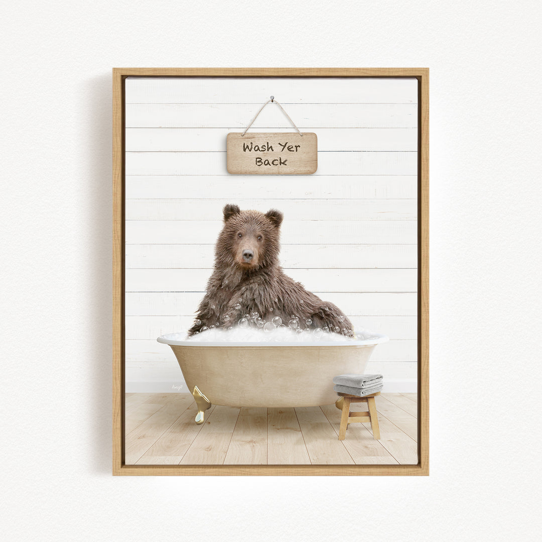 A brown bear sitting in a bathtub filled with bubbles, with a sign above that says "Wash Yer Back".