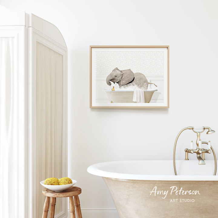 a bathroom scene with a framed picture of an elephant sitting in a bathtub, a wooden stool with a bowl of fruit, and a faucet.