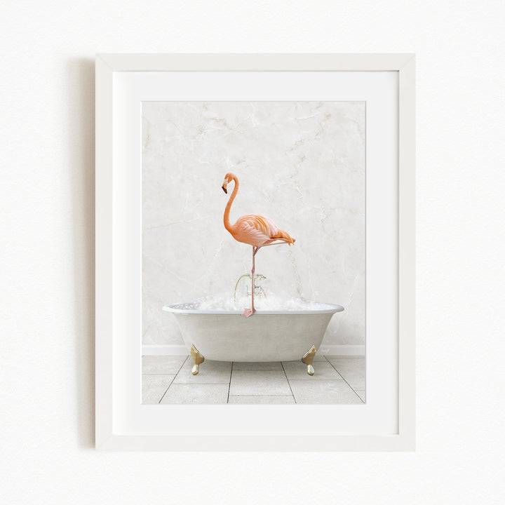 A framed image of a flamingo standing on the edge of a white bathtub filled with water.