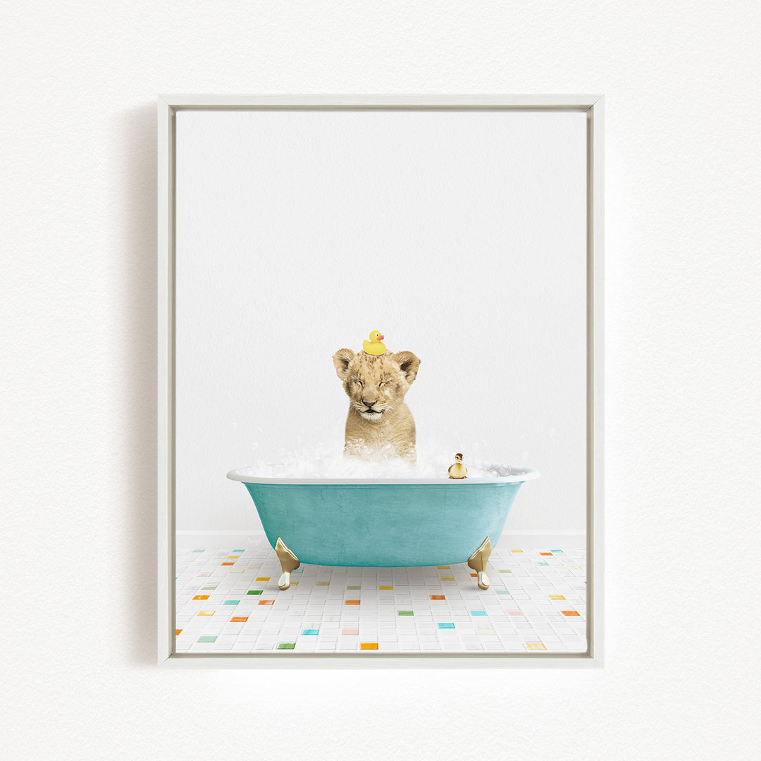A young lion cub is sitting in a blue bathtub filled with bubbles, with two yellow rubber ducks floating on its head.