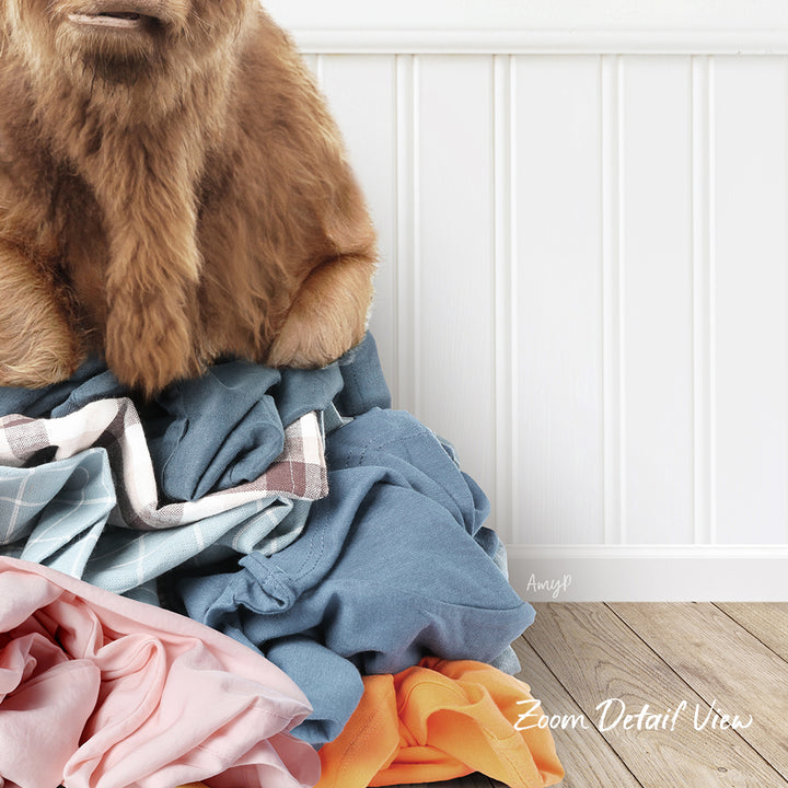 A close-up of a dog's head peeking over a pile of clothes, with a white wall and wooden floor in the background.