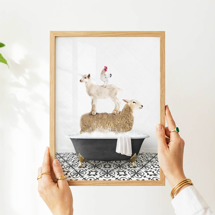 A person's hands are holding a framed picture of a sheep standing on a bathtub, with a chicken perched on top of the sheep.