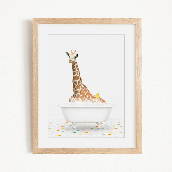 A giraffe sitting in a white bathtub filled with bubbles, with a yellow rubber duck floating on the water.