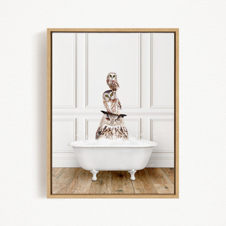 A framed image depicting three owls sitting in a white bathtub, with one owl perched on top of the other two.