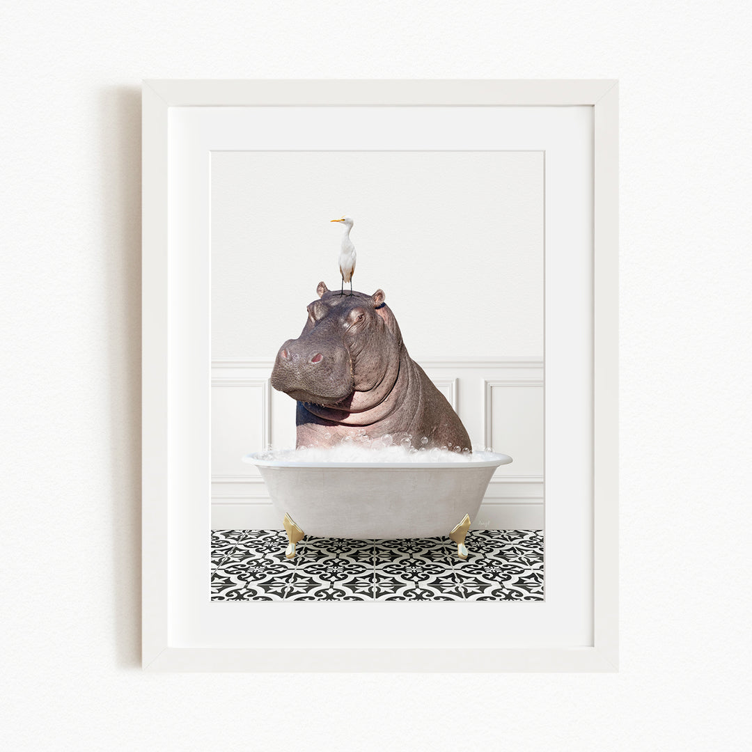 A framed image depicting a large, brown hippopotamus sitting in a white bathtub, with a white bird perched on its head.