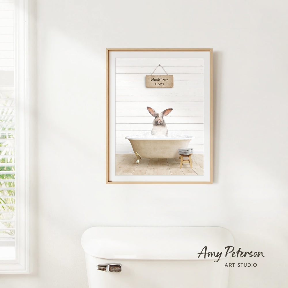 A framed image of a rabbit sitting in a bathtub, with a sign above it that says "Wash Your Ears".