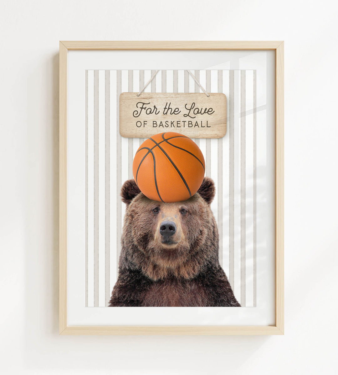 A framed image of a brown bear with a basketball on its head, accompanied by a wooden sign that reads "For the Love of Basketball".