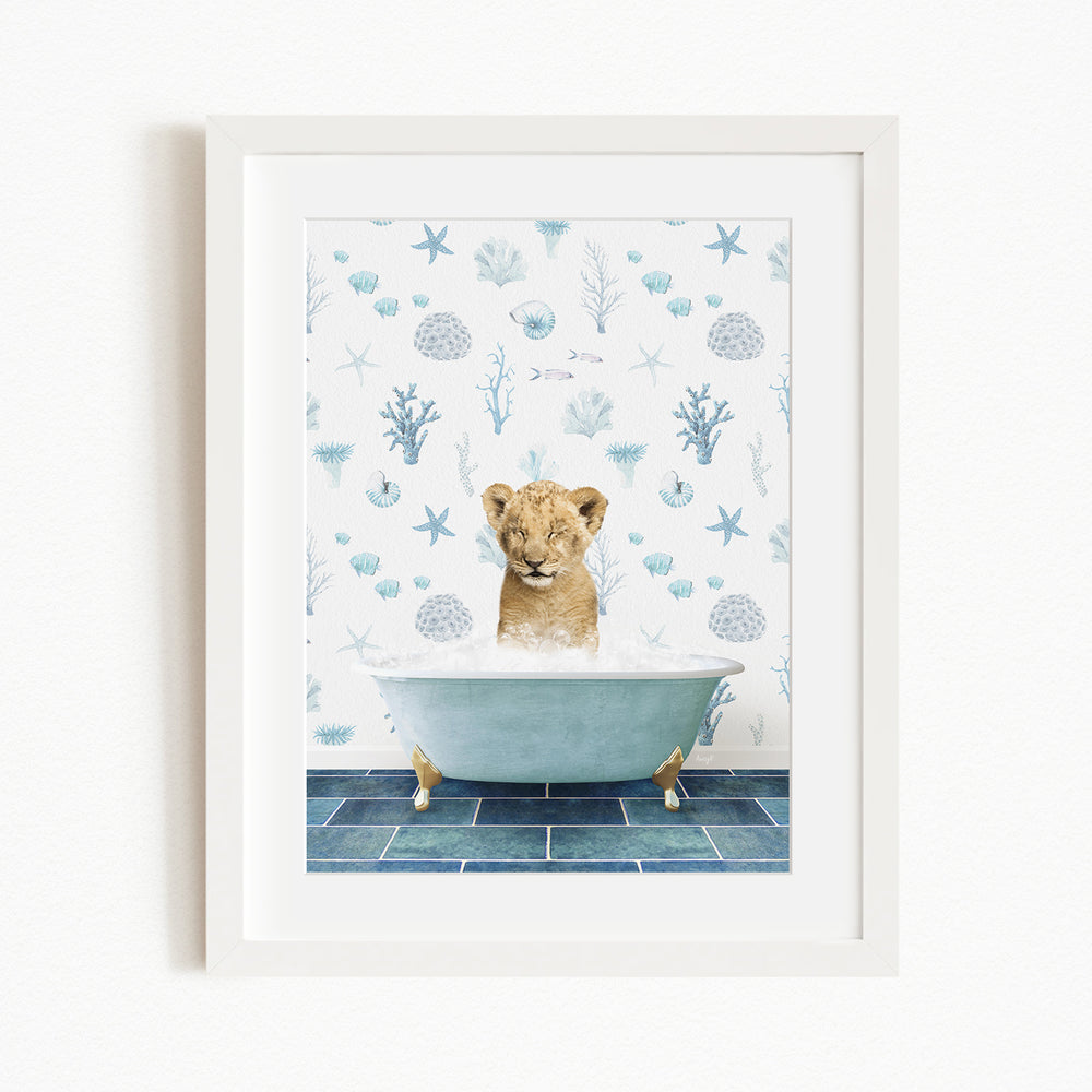 A young lion cub sitting in a bathtub filled with bubbles, surrounded by a blue and white ocean-themed wallpaper.