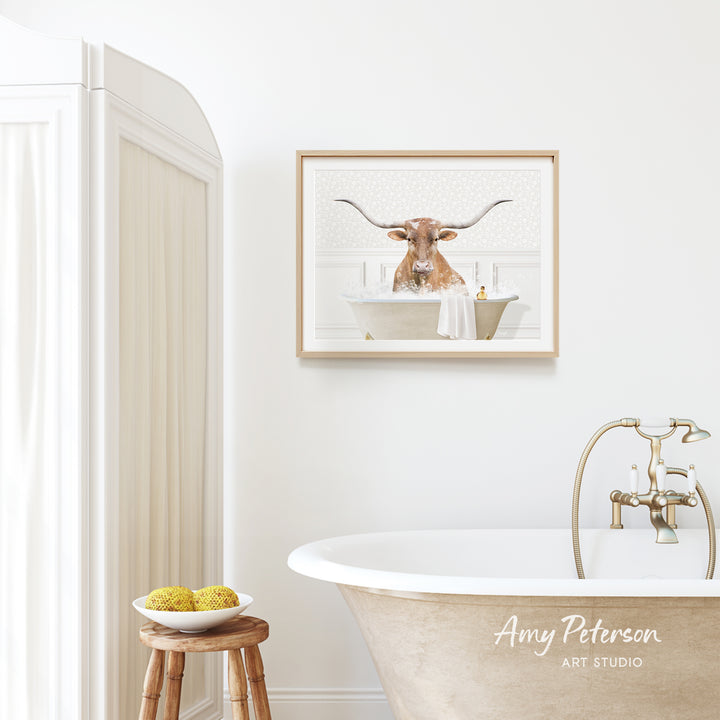 a bathroom with a framed picture of a bull with horns in a bathtub, a wooden stool, and a bowl of fruit.