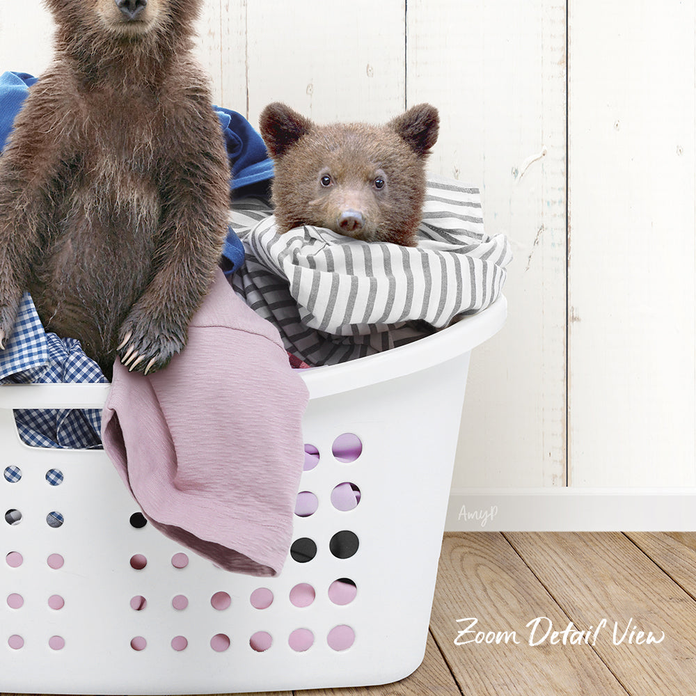 A bear sitting in a laundry basket filled with clothes.