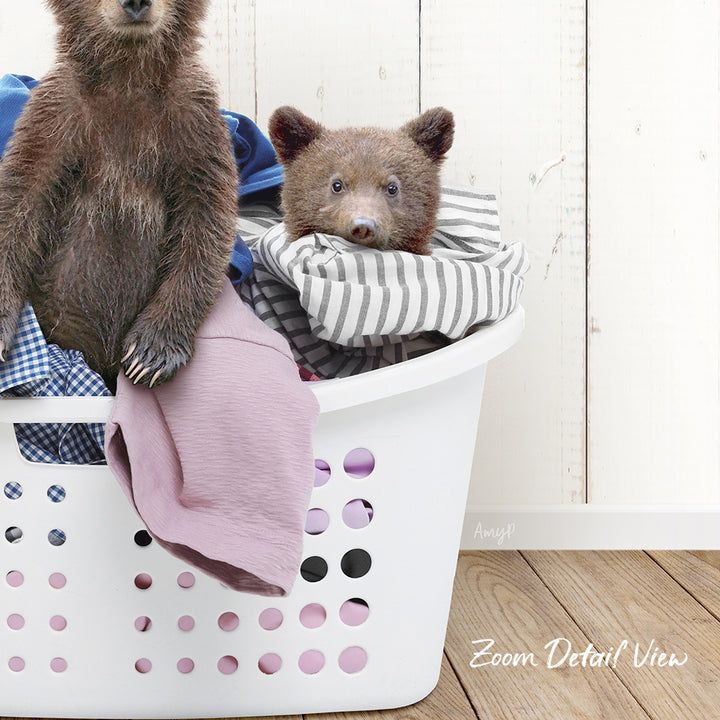 A bear sitting in a laundry basket filled with clothes.