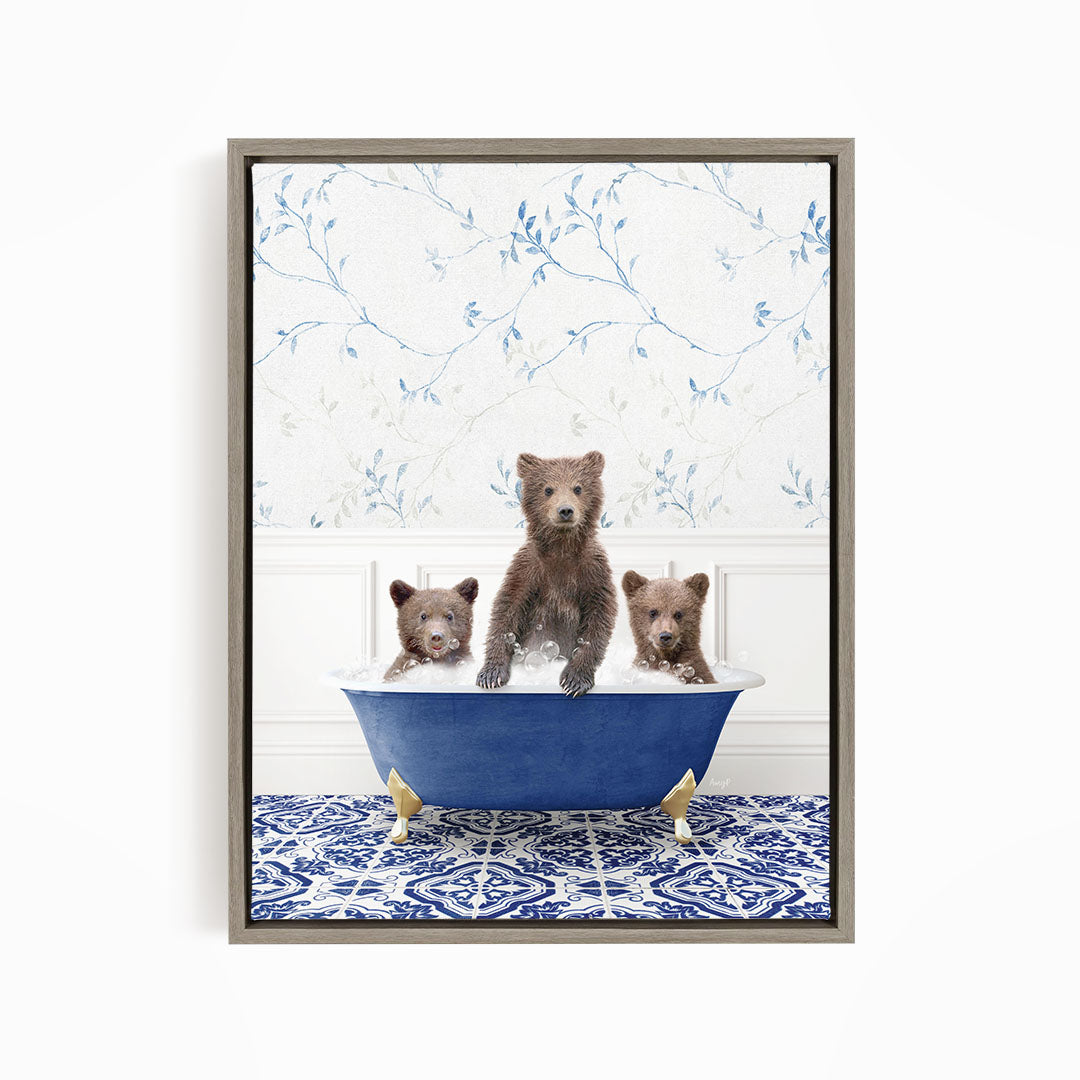 A framed image depicting three bears sitting in a blue bathtub, with a patterned tile floor and a floral wallpaper in the background.