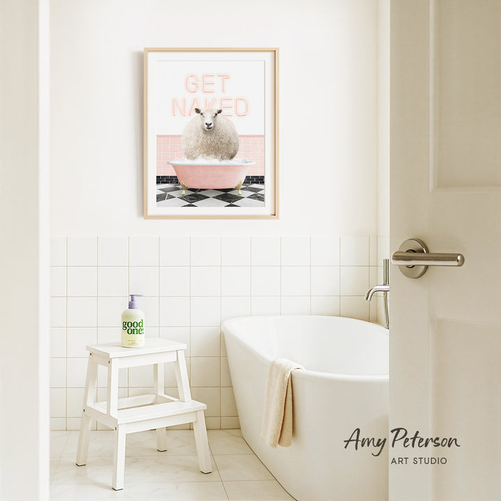 a bathroom with a framed poster of a sheep in a pink bathtub, a white stool, and a white bathtub.