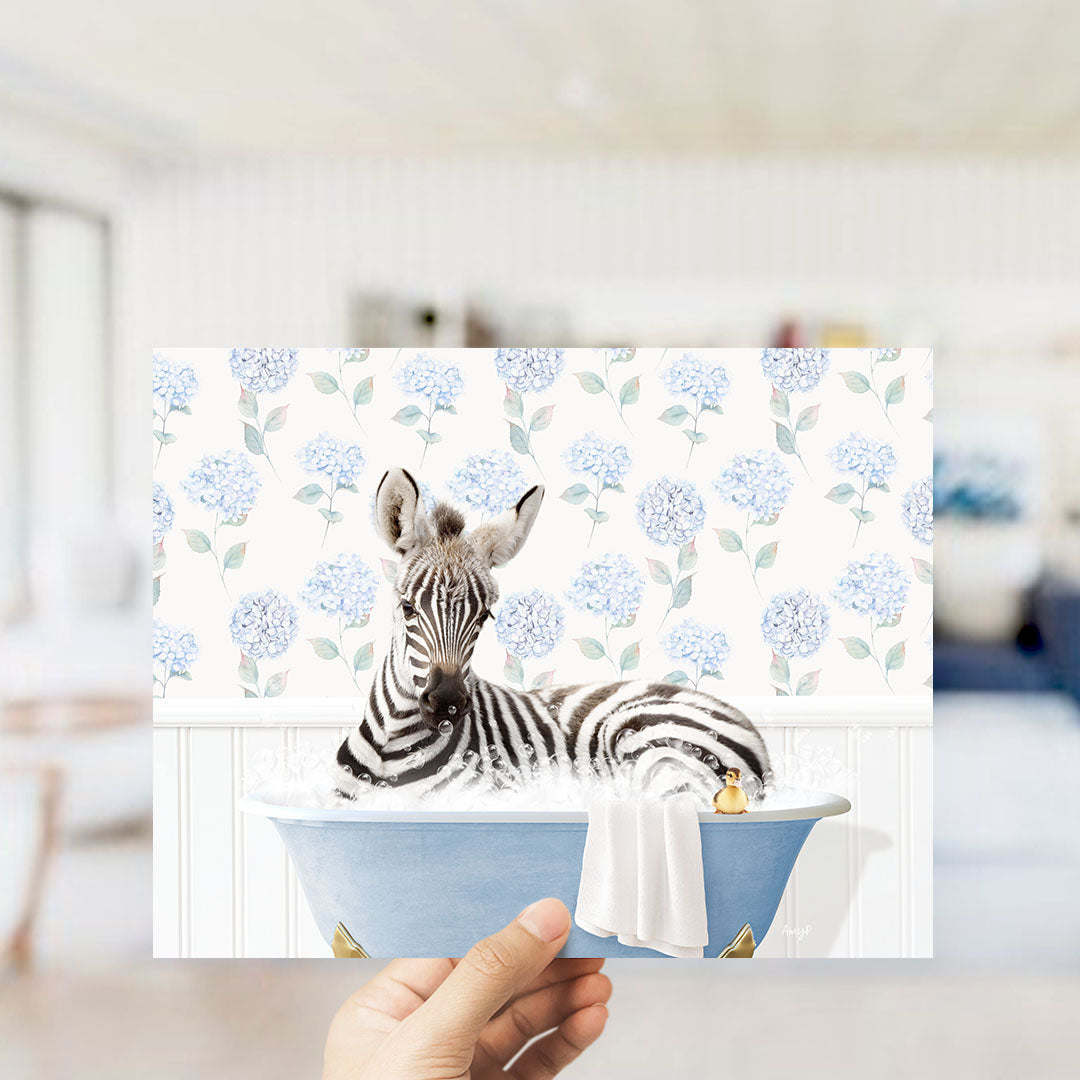 A zebra is sitting in a blue bathtub filled with water, surrounded by a floral pattern.